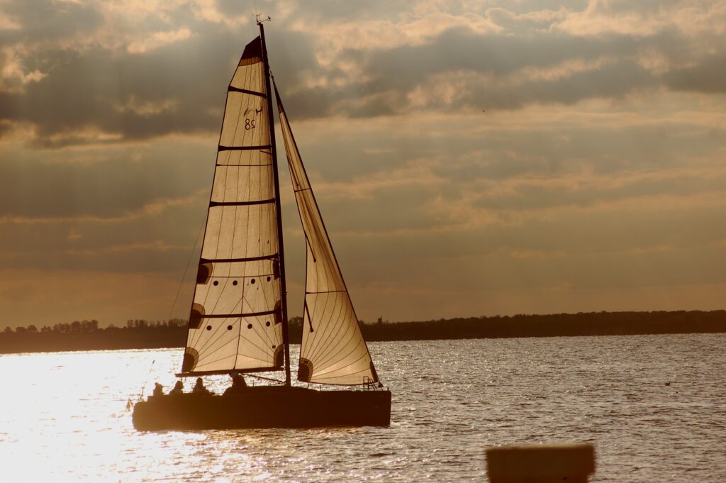 Segelboot in ruhigem Licht auf stillem Wasser, Symbol für Gelassenheit, innere Ruhe und Achtsamkeit